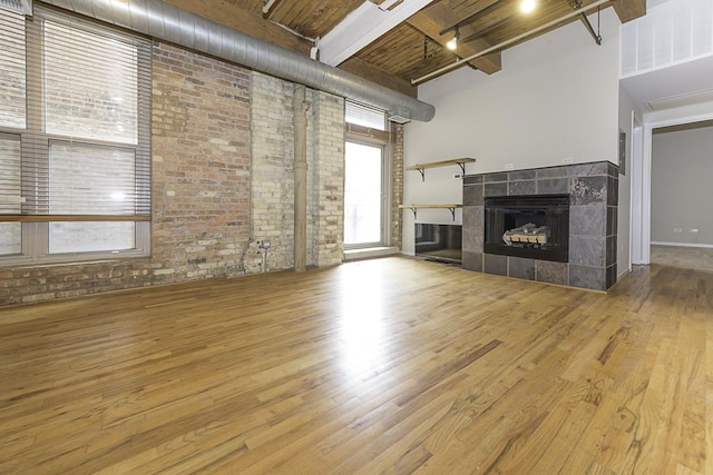 420 S Clinton St Unit 408A, Chicago, IL 60607 - unfurnished living room featuring brick wall, a towering ceiling, wood finished floors, rail lighting, and a fireplace