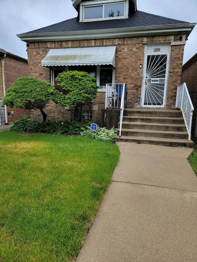 341 W 99th Pl, Chicago, IL 60628 - view of front of property featuring brick siding, a front yard, and roof with shingles