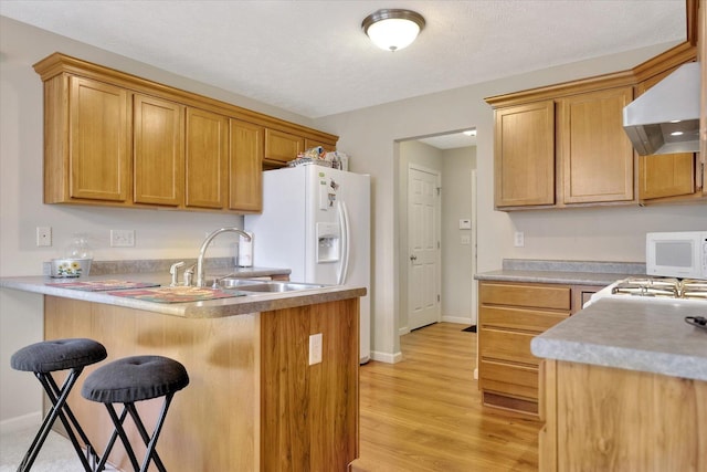 3911 Summer Sage Ct, Champaign, IL 61822 - kitchen with wall chimney exhaust hood, white appliances, a kitchen breakfast bar, a peninsula, and light wood-style flooring