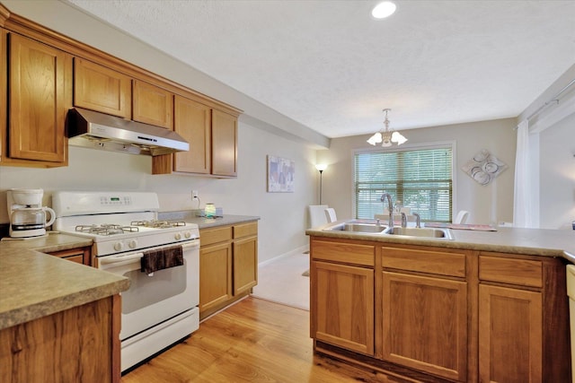 3911 Summer Sage Ct, Champaign, IL 61822 - kitchen featuring under cabinet range hood, white range with gas cooktop, a chandelier, light wood-type flooring, and brown cabinetry
