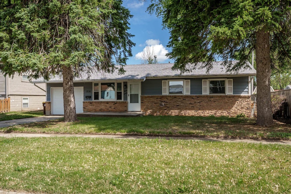 1216 Ramona Ter, Machesney Park, IL 61115 - view of front of home with brick siding, driveway, an attached garage, and a front yard