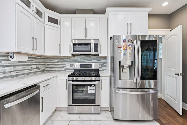 93 Liberty St, West Dundee, IL 60118 - kitchen featuring stainless steel appliances, white cabinetry, light stone counters, backsplash, and glass insert cabinets