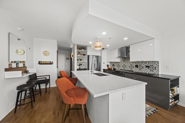 1640 Maple Ave Unit 505, Evanston, IL 60201 - kitchen featuring freestanding refrigerator, a sink, wall chimney range hood, white cabinets, and modern cabinets