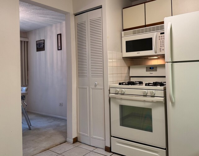 477 Graceland Ave Unit 2F, Des Plaines, IL 60016 - kitchen with white appliances, light colored carpet, light tile patterned floors, baseboards, and backsplash