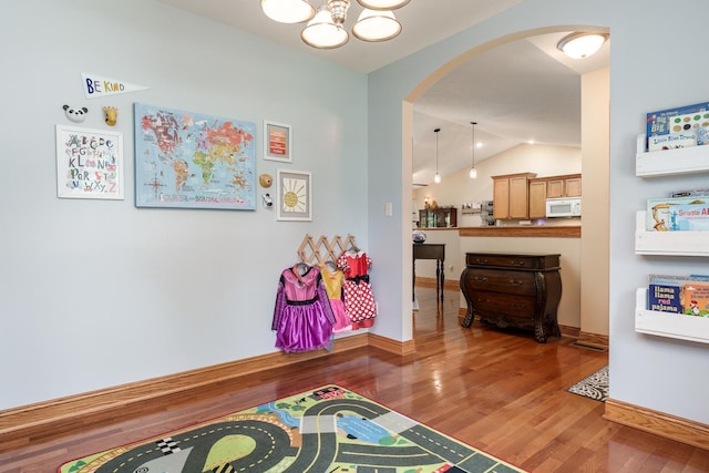 694 Lake Summerset Rd, Davis, IL 61019 - recreation room featuring arched walkways, wood finished floors, a chandelier, vaulted ceiling, and baseboards