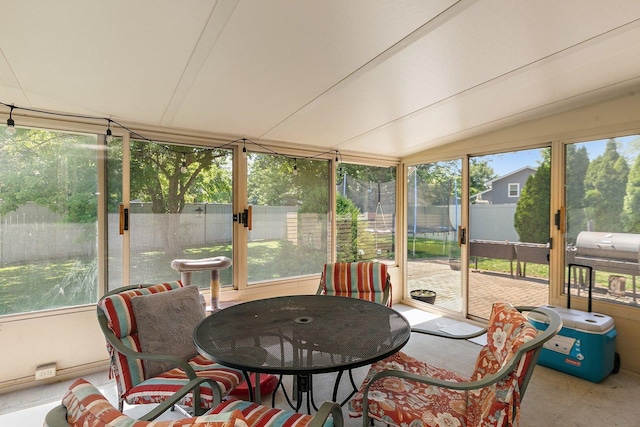 sunroom with healthy amount of natural light, lofted ceiling, and outdoor dining space