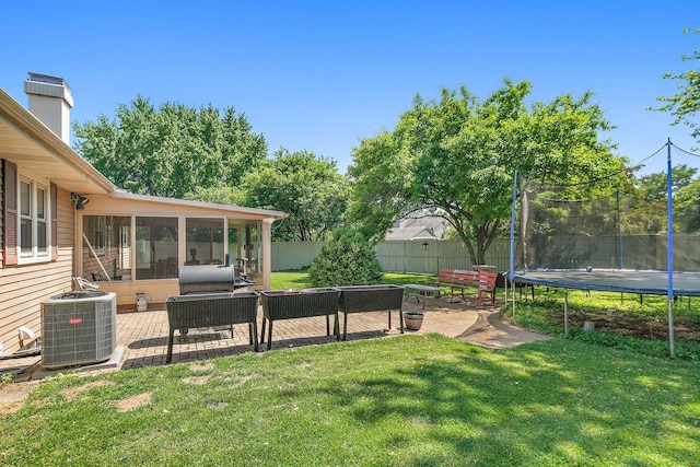 view of yard featuring a trampoline, central AC unit, a sunroom, and a patio area
