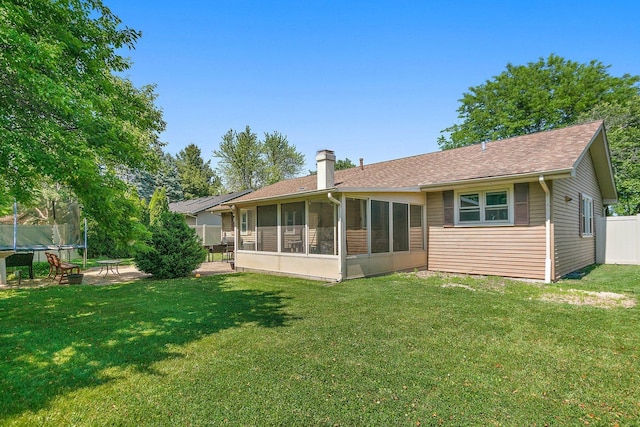 back of house with a trampoline, a chimney, a sunroom, and roof with shingles