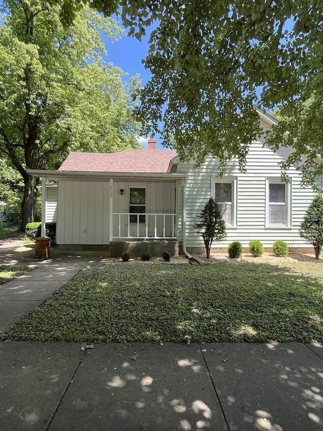 112 W 6th St, Gridley, IL 61744 - view of front facade with driveway, a chimney, a carport, board and batten siding, and roof with shingles