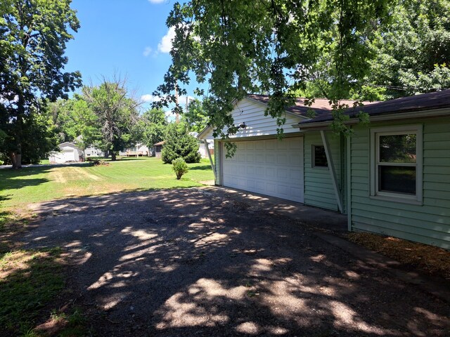 112 W 6th St, Gridley, IL 61744 - view of side of home with driveway, a garage, an outbuilding, and a lawn