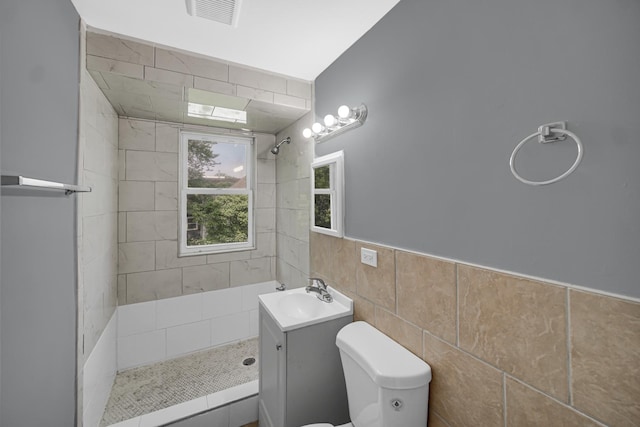 72 E 136th St, Riverdale, IL 60827 - bathroom featuring a tile shower, vanity, tile walls, and wainscoting