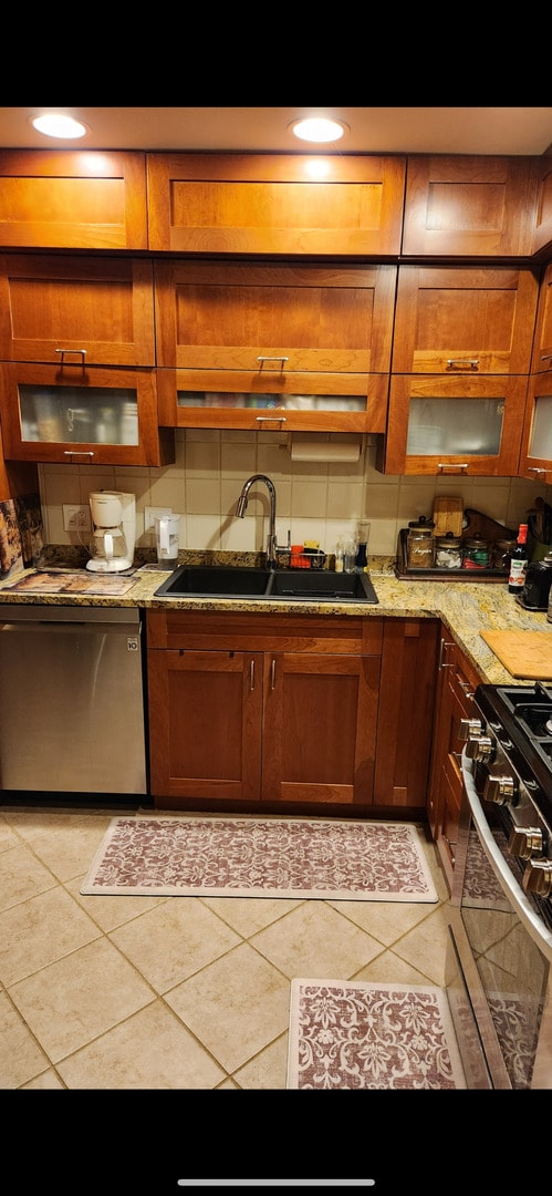 3300 N Carriageway Dr Unit 209, Arlington Heights, IL 60004 - kitchen featuring stainless steel appliances, a sink, light tile patterned floors, and light stone countertops