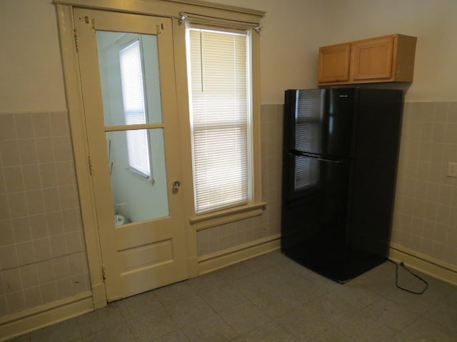 7120 S Eberhart Ave, Chicago, IL 60619 - kitchen with freestanding refrigerator, tile walls, a wainscoted wall, healthy amount of natural light, and light tile patterned floors