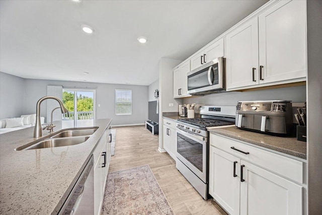 3808 Honeysuckle Ln, Elgin, IL 60124 - kitchen with appliances with stainless steel finishes, a sink, white cabinets, light stone counters, and open floor plan