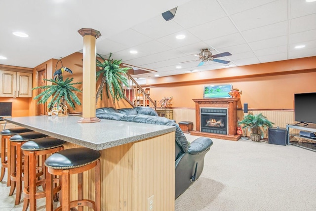 5N647 Forest Glen Ln, Saint Charles, IL 60175 - kitchen featuring carpet, ceiling fan, a breakfast bar area, wainscoting, and a lit fireplace