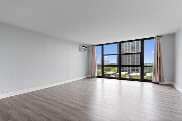 2901 S Michigan Ave Unit 903, Chicago, IL 60616 - spare room with a wall mounted AC, wood finished floors, healthy amount of natural light, expansive windows, and baseboards
