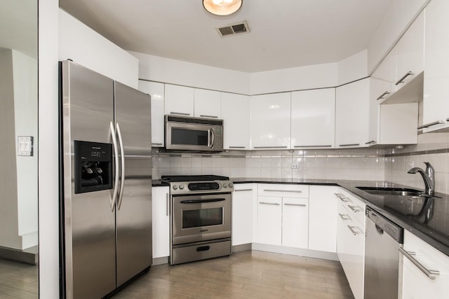 125 Boardwalk Pl Unit 101, Park Ridge, IL 60068 - kitchen featuring appliances with stainless steel finishes, a sink, white cabinetry, wood finished floors, and tasteful backsplash