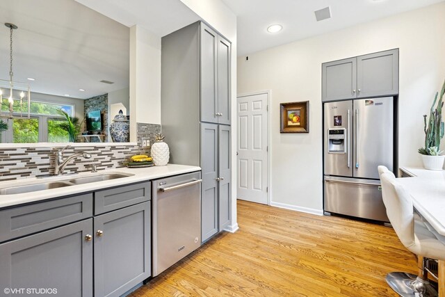 5844 N Hermitage Ave Unit A, Chicago, IL 60660 - kitchen with stainless steel appliances, gray cabinetry, backsplash, a sink, and recessed lighting
