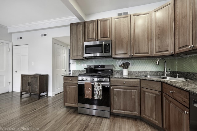 4005 N Southport Ave Unit 2, Chicago, IL 60613 - kitchen with stainless steel appliances, a sink, decorative backsplash, wood finished floors, and ornamental molding