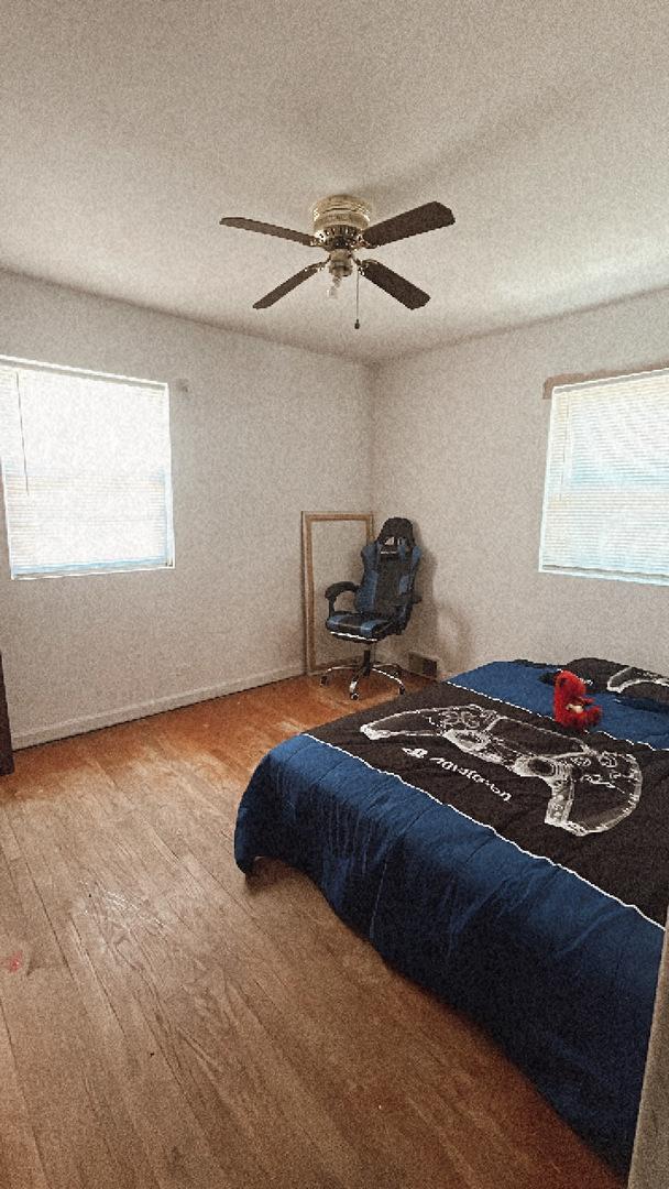 11138 Shaw St, Westchester, IL 60154 - bedroom featuring multiple windows, wood finished floors, a textured ceiling, and a ceiling fan