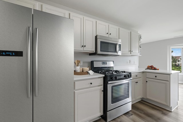19463 Manchester Dr Unit 2, Mokena, IL 60448 - kitchen featuring appliances with stainless steel finishes, a peninsula, light wood finished floors, light countertops, and white cabinetry