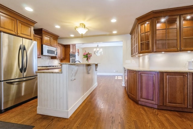 230 S Constitution Dr, Aurora, IL 60506 - kitchen with appliances with stainless steel finishes, brown cabinetry, baseboards, glass insert cabinets, and dark wood finished floors