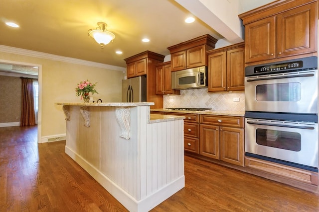 230 S Constitution Dr, Aurora, IL 60506 - kitchen with appliances with stainless steel finishes, brown cabinets, dark wood finished floors, light stone counters, and ornamental molding