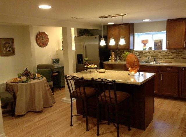 2655 W 97th Pl, Evergreen Park, IL 60805 - kitchen featuring stainless steel refrigerator with ice dispenser, a sink, a breakfast bar, a center island, and light wood-style flooring