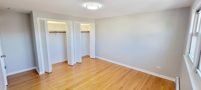 1353 Perry St Unit 6, Des Plaines, IL 60016 - unfurnished bedroom featuring light wood-style flooring, two closets, baseboards, and a baseboard radiator