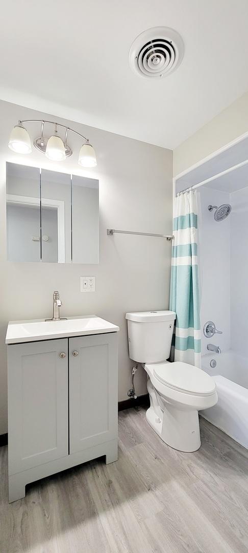 1353 Perry St Unit 6, Des Plaines, IL 60016 - full bath with wood finished floors, vanity, toilet, and shower / bathtub combination with curtain