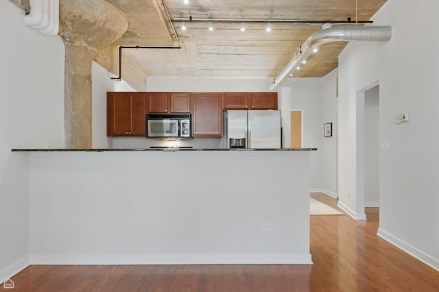 1111 W 14th Pl Unit 211, Chicago, IL 60608 - kitchen featuring stainless steel appliances, dark countertops, rail lighting, wood finished floors, and baseboards