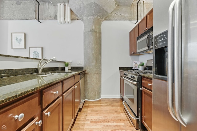 1111 W 14th Pl Unit 211, Chicago, IL 60608 - kitchen with stainless steel appliances, a sink, light wood-style floors, dark stone counters, and brown cabinetry