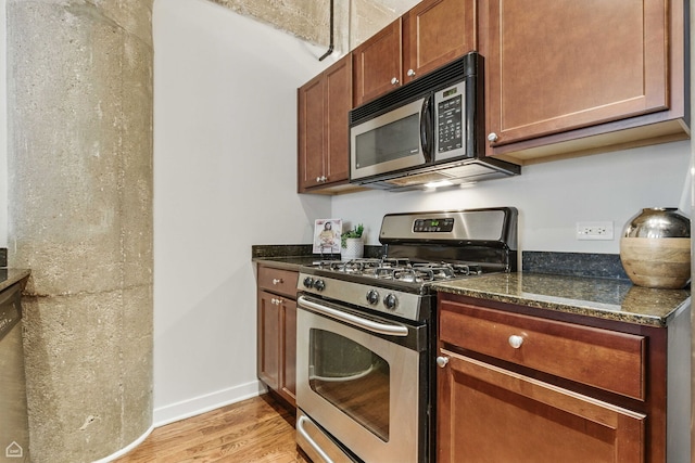 1111 W 14th Pl Unit 211, Chicago, IL 60608 - kitchen with stainless steel range with gas stovetop, black microwave, light wood-style flooring, baseboards, and dark stone countertops