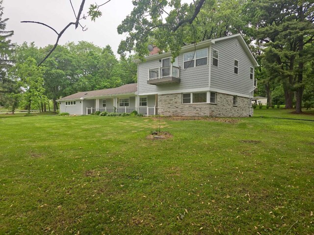 1762 W Palatine Rd, Inverness, IL 60067 - view of front of house featuring a balcony, stone siding, a front yard, and view of wooded area