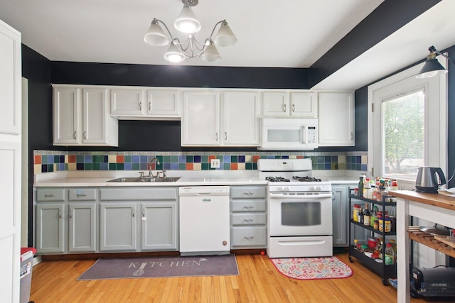 6100 Ridgeway Dr, Woodridge, IL 60517 - kitchen with white appliances, light countertops, a chandelier, light wood-type flooring, and backsplash