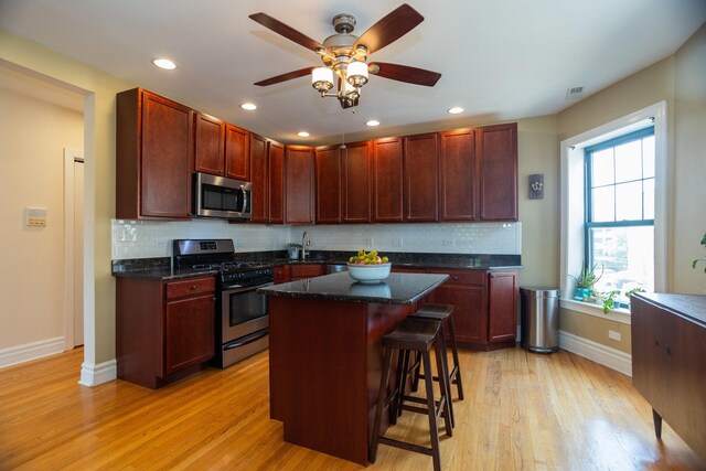 1239 W Jarvis Ave Unit 3, Chicago, IL 60626 - kitchen featuring appliances with stainless steel finishes, baseboards, a breakfast bar area, tasteful backsplash, and light wood finished floors
