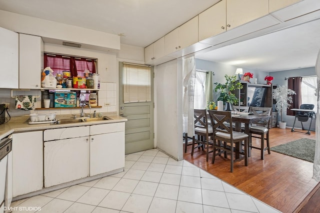 5032 Crain St, Skokie, IL 60077 - kitchen with a sink, light countertops, light tile patterned flooring, white cabinets, and dishwashing machine