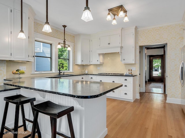 412 7th Ave, La Grange, IL 60525 - kitchen featuring wallpapered walls, a peninsula, dark countertops, white cabinetry, and ornamental molding
