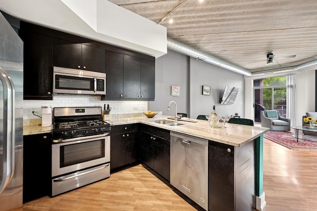 3201 W Leland Ave Unit 205, Chicago, IL 60625 - kitchen featuring appliances with stainless steel finishes, a sink, dark cabinets, a peninsula, and light wood finished floors