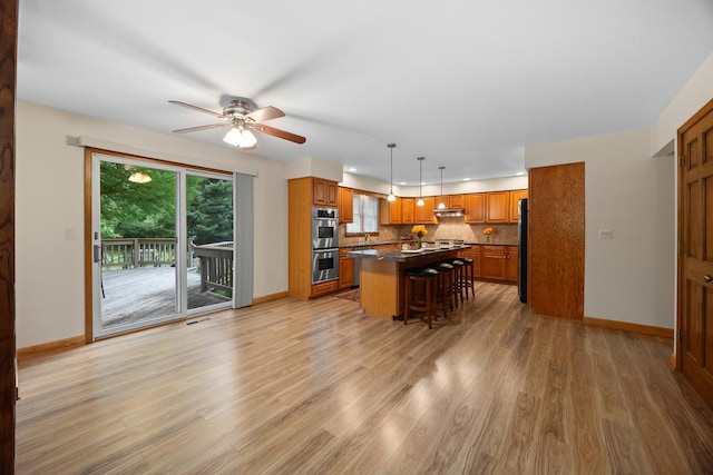 1291 Acorn Ct, Sleepy Hollow, IL 60118 - kitchen featuring appliances with stainless steel finishes, brown cabinetry, dark countertops, ceiling fan, and a kitchen island