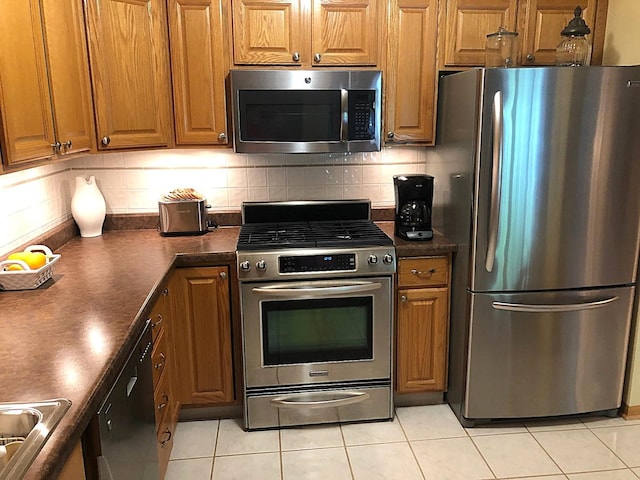 460 S NW Hwy Unit 409, Park Ridge, IL 60068 - kitchen featuring appliances with stainless steel finishes, dark countertops, brown cabinetry, and light tile patterned flooring