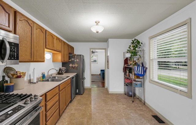 3310 Saratoga Dr, Champaign, IL 61821 - kitchen with a sink, appliances with stainless steel finishes, light countertops, brown cabinets, and baseboards