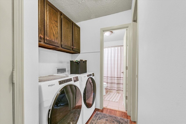 3310 Saratoga Dr, Champaign, IL 61821 - washroom featuring washing machine and clothes dryer, cabinet space, a textured ceiling, and wood finished floors