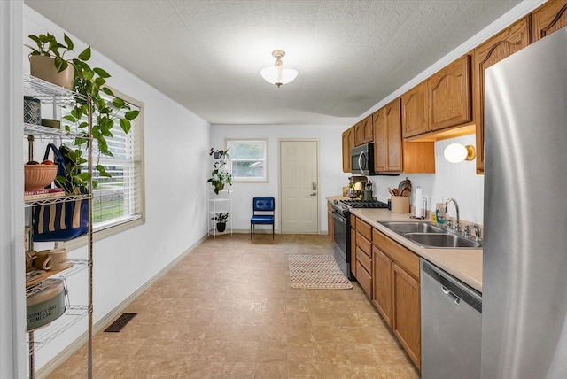3310 Saratoga Dr, Champaign, IL 61821 - kitchen featuring stainless steel appliances, a sink, light countertops, brown cabinets, and baseboards