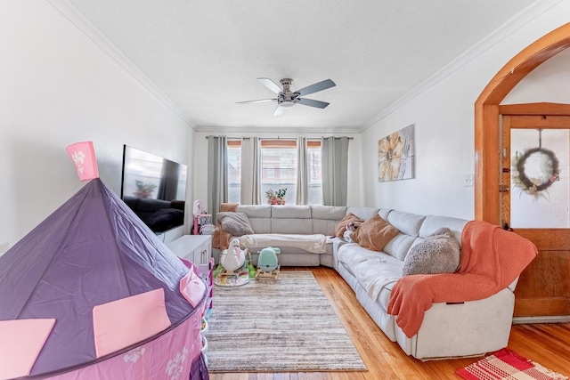 1909 Harvey Ave, Berwyn, IL 60402 - living area with crown molding, light wood-style floors, arched walkways, a ceiling fan, and a textured ceiling