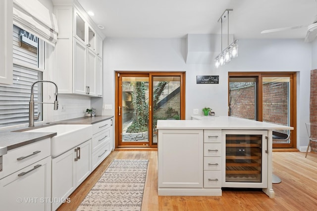 1636 N Cleveland Ave, Chicago, IL 60614 - kitchen featuring beverage cooler, a sink, white cabinetry, light wood-style floors, and glass insert cabinets