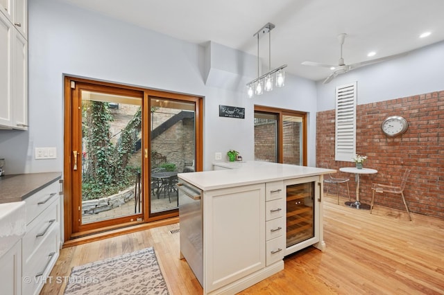 1636 N Cleveland Ave, Chicago, IL 60614 - kitchen with beverage cooler, brick wall, light wood-style flooring, ceiling fan, and white cabinetry