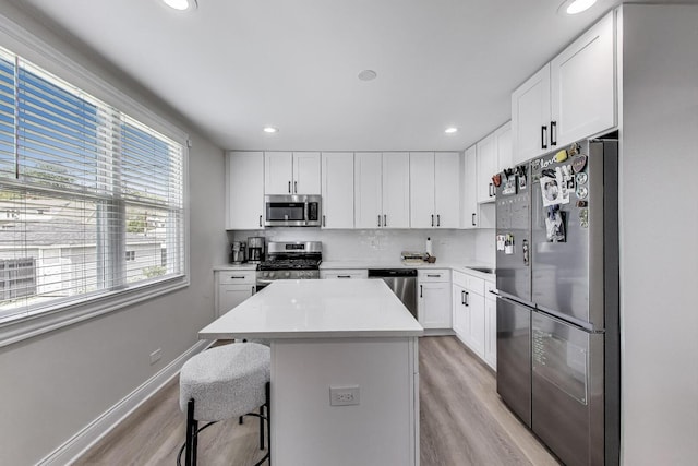 529 Circle Ave, Forest Park, IL 60130 - kitchen featuring appliances with stainless steel finishes, light wood-style floors, a kitchen island, a breakfast bar, and light countertops