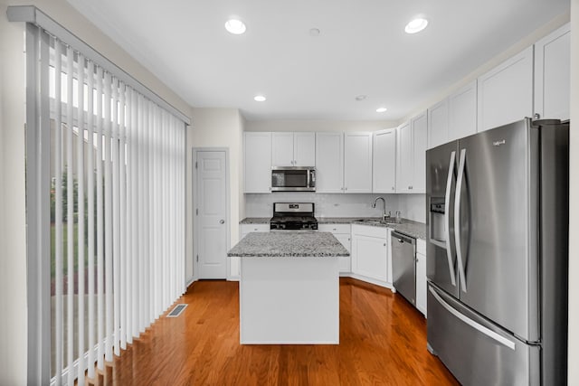 192 Owen St, Matteson, IL 60443 - kitchen featuring appliances with stainless steel finishes, a sink, a kitchen island, wood finished floors, and white cabinets