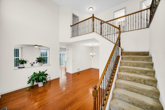 192 Owen St, Matteson, IL 60443 - stairs featuring a ceiling fan, wood finished floors, a chandelier, a towering ceiling, and baseboards